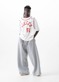 on-body shot of a model wearing the Pieces 91 Jersey Tee White and Red front view with grey sweatpants Pieces 91 Jersey Tee White - Image 5 | Authenticated at Pieces Los Angeles