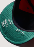 Pieces God vs Devil Baseball Cap Hat Red Navy close up of underneath the brim, green underbrim with white text Pieces God vs Devil Baseball Cap Red Navy - Image 4 | Authenticated at Pieces Los Angeles