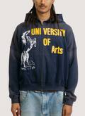 on-body shot of a man wearing the Pieces Academia Zippered Sweatshirt hoodie Vintage Navy blue  with yellow text that says University of Arts and a logo of a horse Pieces Academia Zippered Sweatshirt Vintage Navy - Image 3 | Authenticated at Pieces Los Angeles