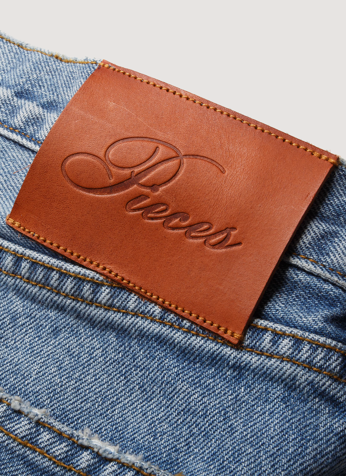 Pieces Alexander Denim Washed Indigo Blue Jeans close up of back side showing Pieces text stitched onto the back leather patch