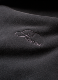 Close up of the cursive Pieces logo on the Pieces Basic Program Zip Up Sweatshirt Washed Black grey hoodie Pieces Basic Program Zip Up Sweatshirt Washed Black - Image 6 | Authenticated at Pieces Los Angeles