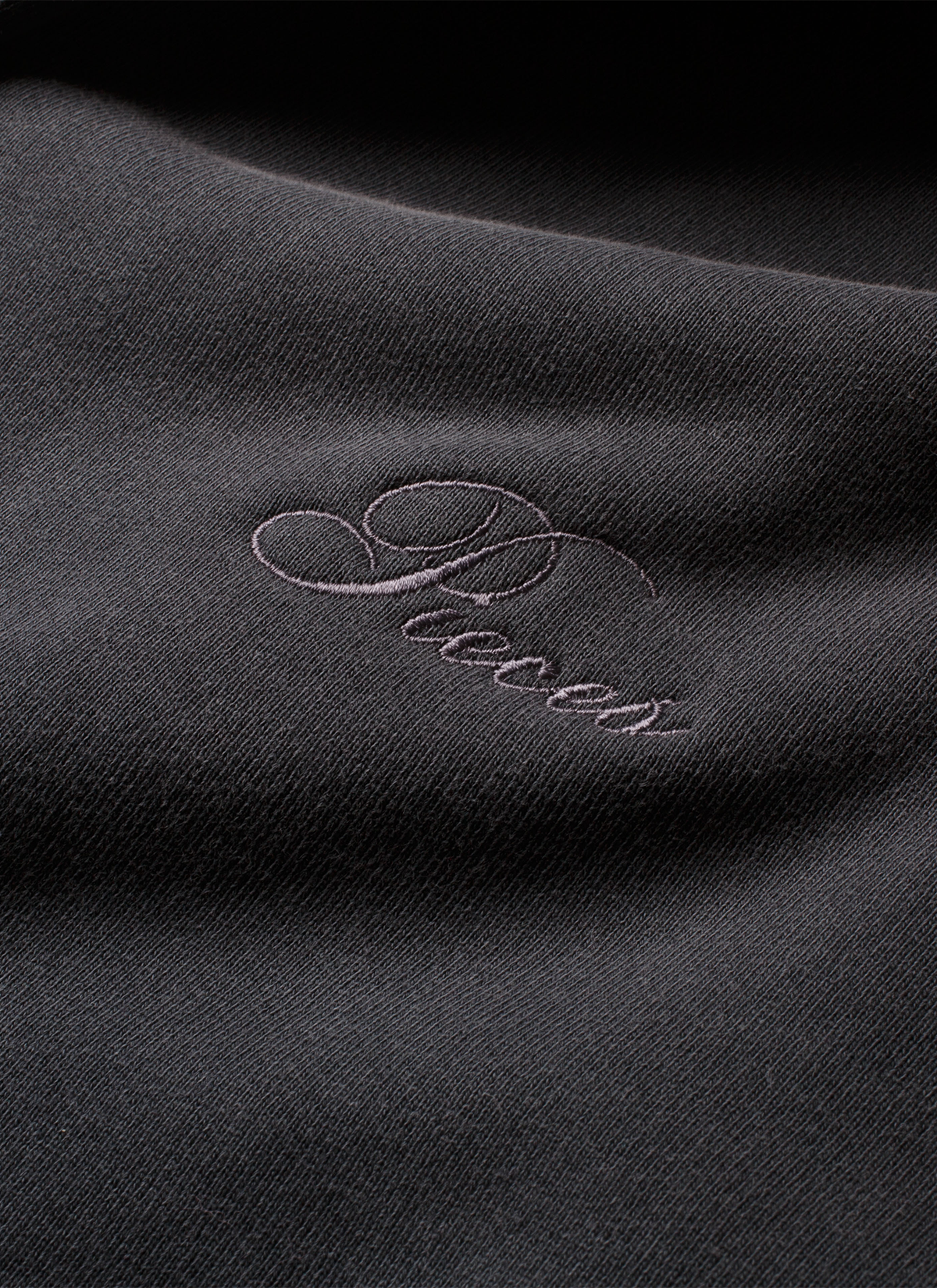 Close up of the cursive Pieces logo on the Pieces Basic Program Zip Up Sweatshirt Washed Black grey hoodie Pieces Basic Program Zip Up Sweatshirt Washed Black - Image 6 | Authenticated at Pieces Los Angeles