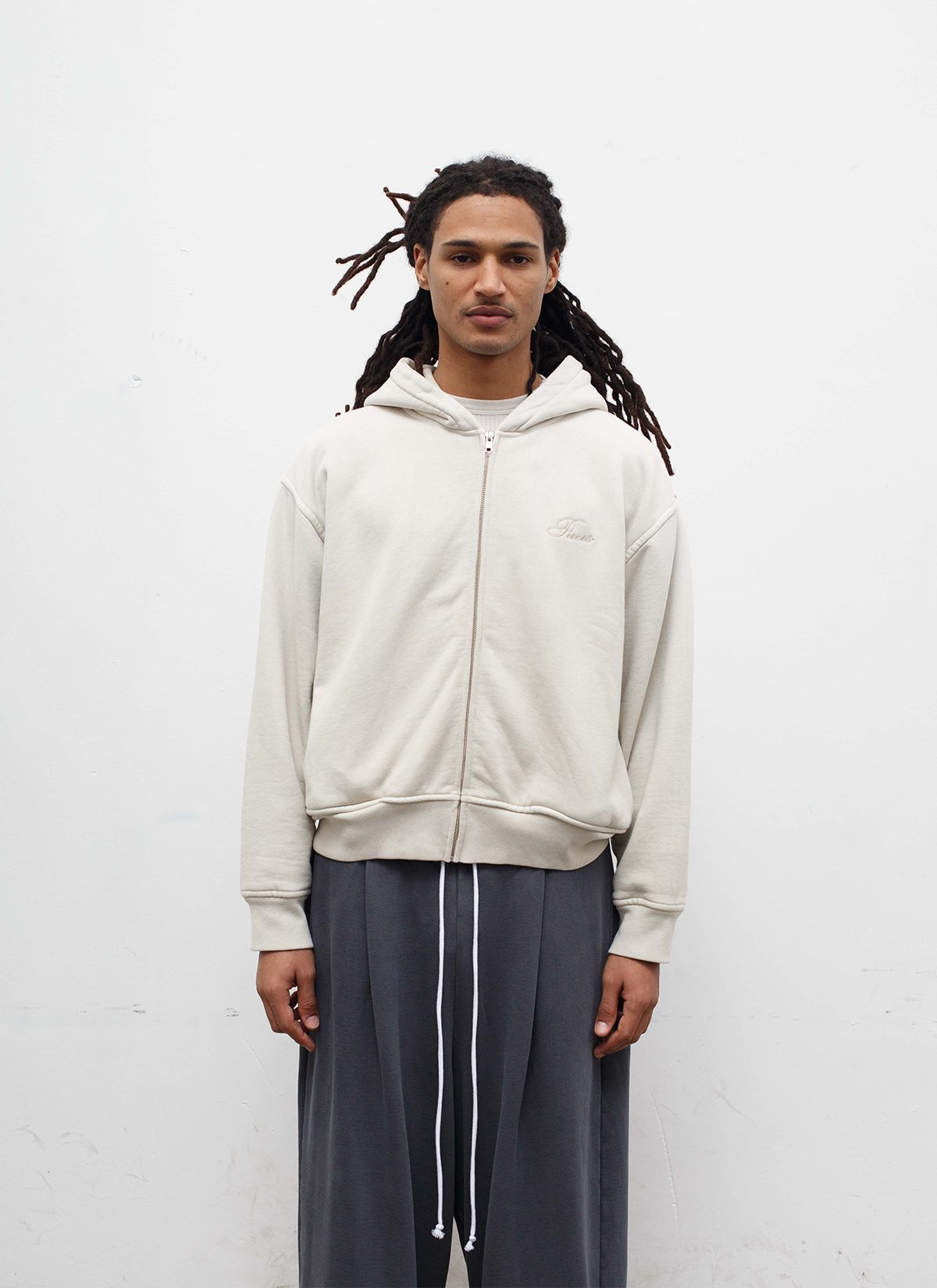 Man wearing sweatpants and the Pieces Basic Program Zip Up Sweatshirt Bone White Off-White front view Pieces Basic Program Zip Up Sweatshirt Bone - Image 3 | Authenticated at Pieces Los Angeles