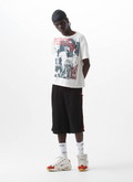 Man wearing the Pieces Elongated Mesh Shorts Black Red with black drawstrings and the Pieces Chasing Perfection Tee Ivory, front view Pieces Elongated Mesh Shorts Black Red - Image 4 | Authenticated at Pieces Los Angeles