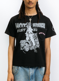 Man wearing the Pieces Fast Bikes Pocket Tee Shirt Vintage Black with graphic of woman riding a motorcycle, with a front pocket with pink text on it, front view Pieces Fast Bikes Pocket Tee Vintage Black - Image 5 | Authenticated at Pieces Los Angeles