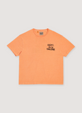 Gallery Dept. French Logo Tee Shirt Flo Orange with printed black logo text that says Dept de la Galerie, vintage wash and dye methods, boxy, flowy fit, front view Gallery Dept. French Logo Tee Flo Orange - Image 1 | Authenticated at Pieces Los Angeles