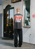 man standing in front of a ticket booth wearing the Pieces Influence Cut Off Vintage faded Black tank top facing away from the camera Pieces Influence Cut Off Vintage Black - Image 6 | Authenticated at Pieces Los Angeles