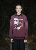 Man standing in the forest at night wearing the Pieces Inhumane Half Zip Sweatshirt Vintage Maroon hoodie with half-zip zipper, graphics and text on the hoodie Pieces Inhumane Half Zip Sweatshirt Vintage Maroon - Image 4 | Authenticated at Pieces Los Angeles