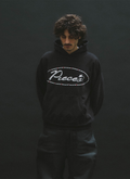 Man wearing the Pieces Jeweled Sweatshirt Black Hoodie with a cursive Pieces logo surrounded by red rhinestone jewels front view Pieces Jeweled Sweatshirt Black - Image 6 | Authenticated at Pieces Los Angeles
