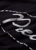 Pieces Jeweled Sweatshirt Black Hoodie with a cursive Pieces logo surrounded by blue rhinestone jewels front view, close up Pieces Jeweled Sweatshirt Black - Image 4 | Authenticated at Pieces Los Angeles