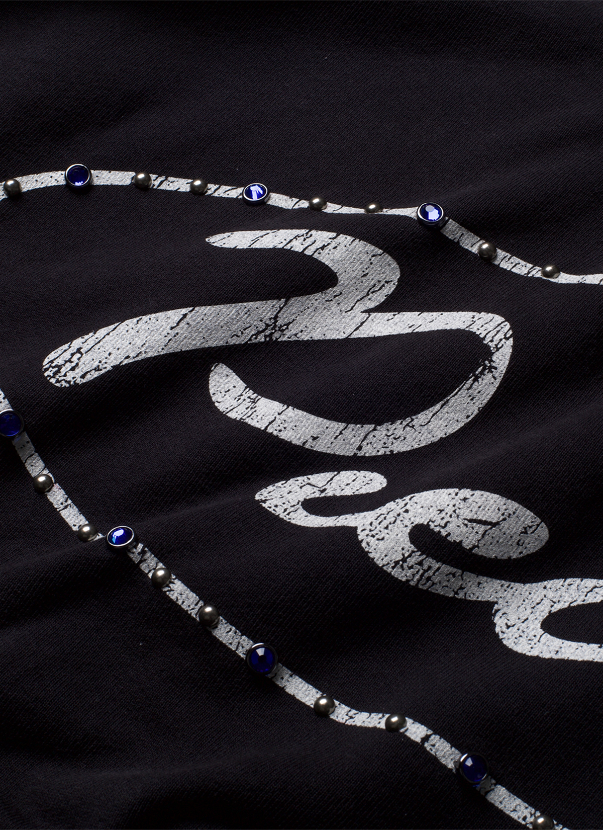 Pieces Jeweled Sweatshirt Black Hoodie with a cursive Pieces logo surrounded by blue rhinestone jewels front view, close up Pieces Jeweled Sweatshirt Black - Image 4 | Authenticated at Pieces Los Angeles