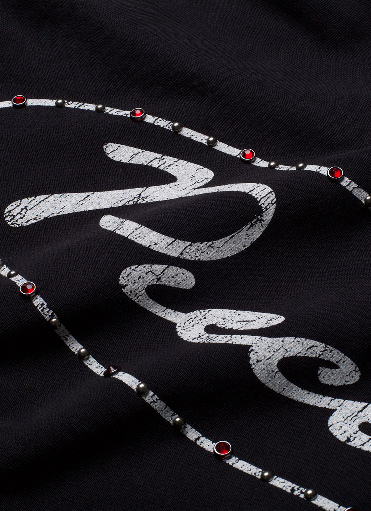 Pieces Jeweled Sweatshirt Black Hoodie with a cursive Pieces logo surrounded by red rhinestone jewels front view, close up Pieces Jeweled Sweatshirt Black - Image 5 | Authenticated at Pieces Los Angeles