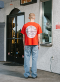 Man standing in front of store wearing the Pieces Mental Health Tee shirt Vintage Red with his back to the camera Pieces Mental Health Tee Vintage Red - Image 7 | Authenticated at Pieces Los Angeles