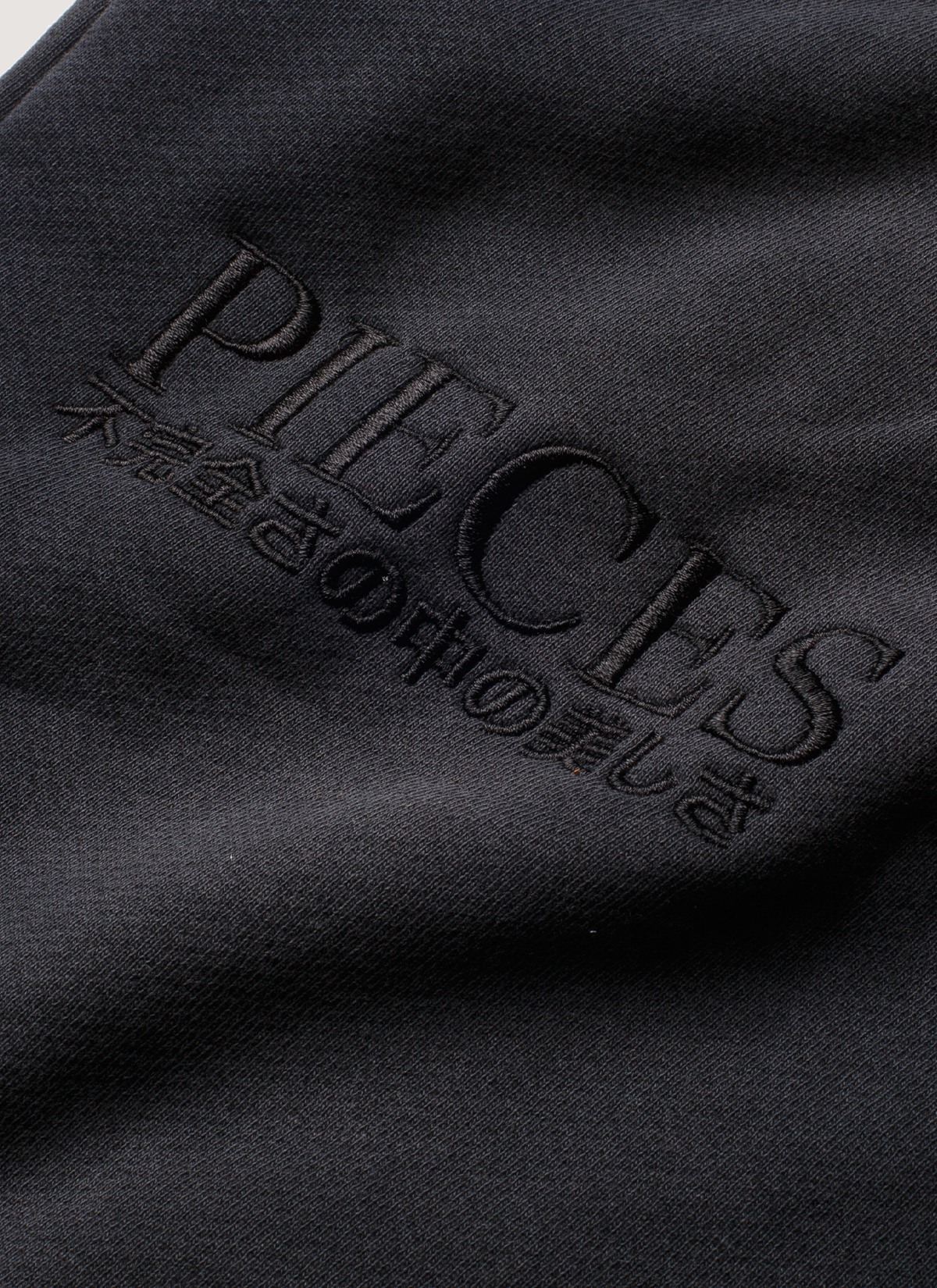 Pieces Repair Pleated Sweatpants Vintage Black close up view of Pieces text and japanese text underneath