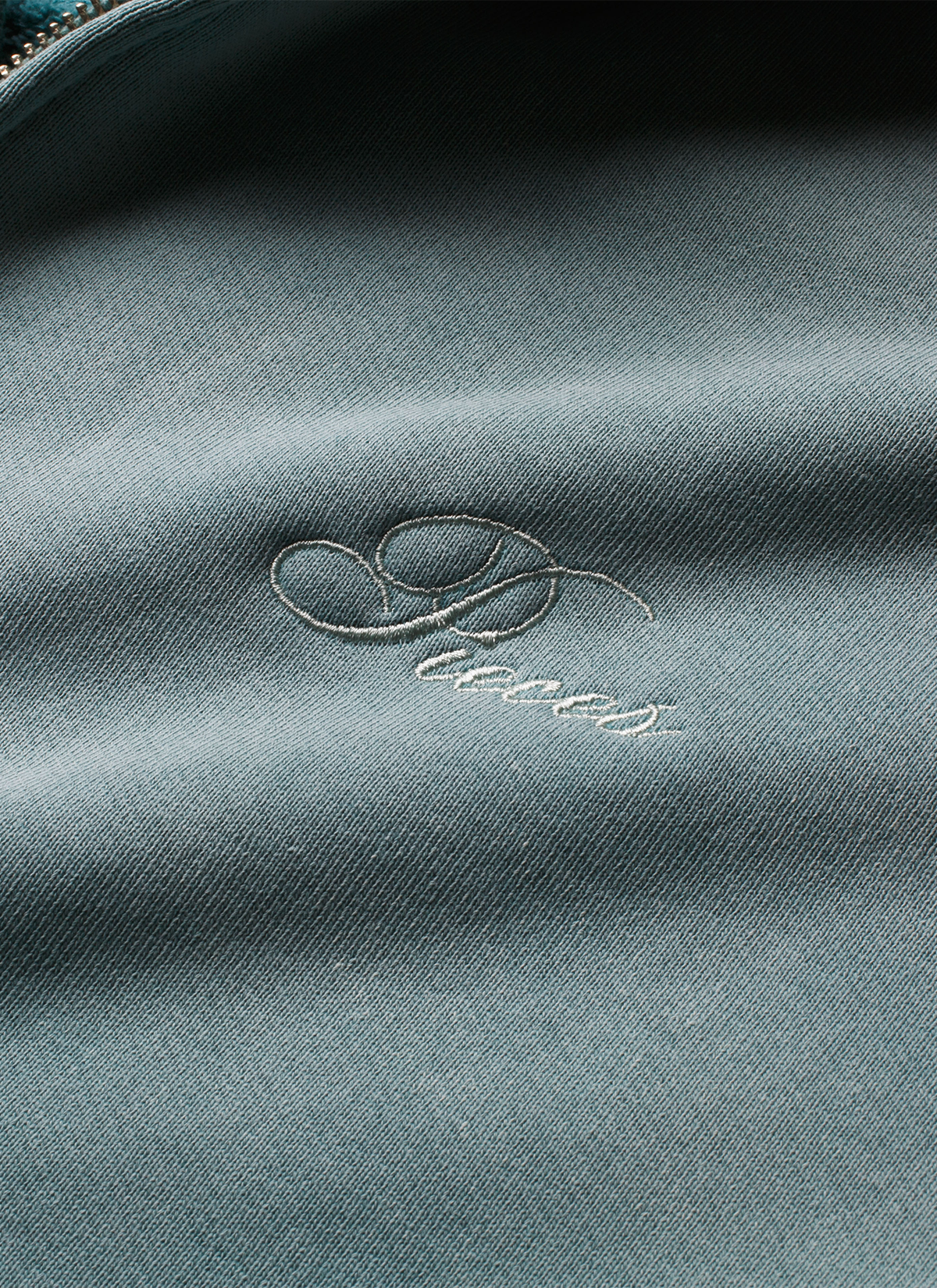 Pieces Basic Program Zip Up Sweatshirt Seafoam Green Blue close up view of cursive Pieces logo on front Pieces Basic Program Zip Up Sweatshirt Seafoam - Image 6 | Authenticated at Pieces Los Angeles