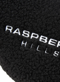 GV Gallery Stacy From The Woods Slips Black slip on slides, plush wool upper, rubber traction sole, embroidered logos, close up view of embroidered logo that says Raspberry Hills GV Gallery Stacy From The Woods Slips Black - Image 2 | Authenticated at Pieces Los Angeles