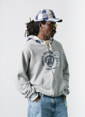 Man wearing the Pieces TKYPD Plaid Hooded Zip Up Sweatshirt Heather Grey with checkered blue white hood, side view with the Pieces Street Hat Cream Navy Plaid Pieces TKYPD Plaid Hooded Zip Up Sweatshirt Heather Grey - Image 4 | Authenticated at Pieces Los Angeles