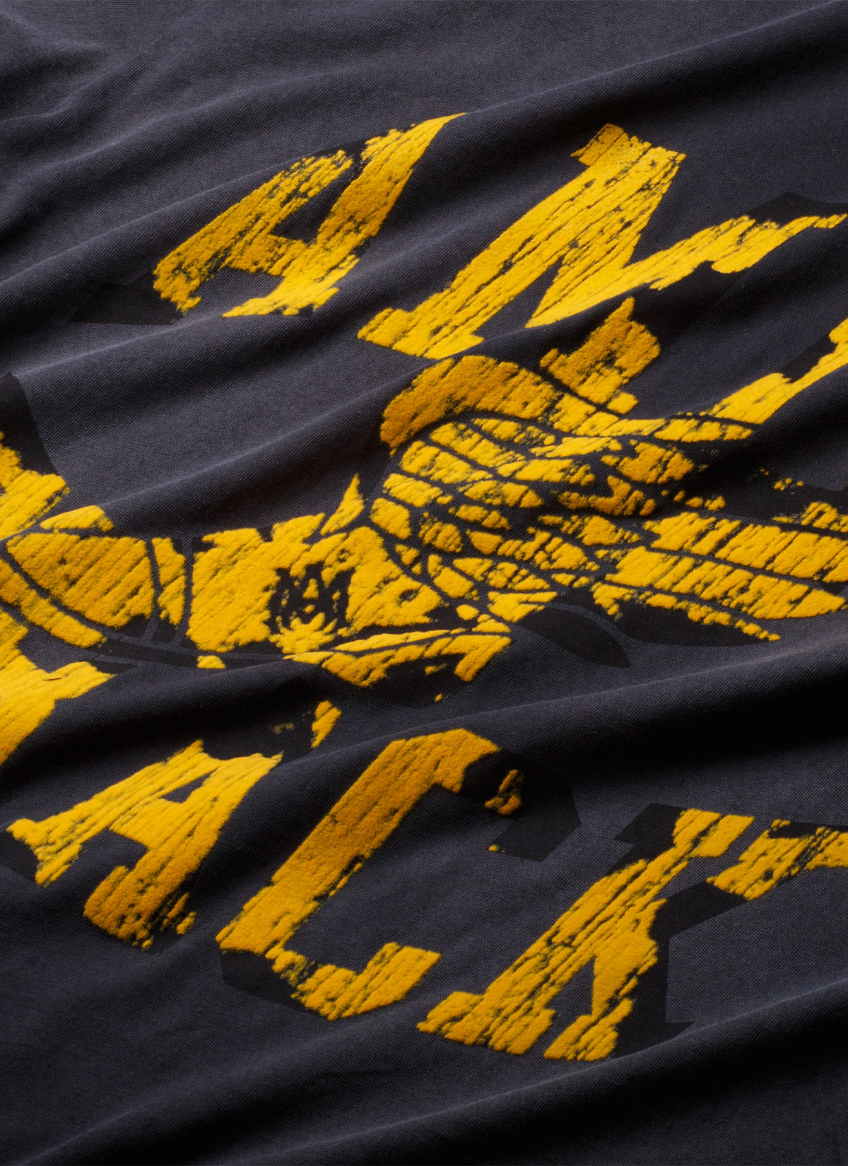 Close up of the Amiri Track Tee shirt Washed Black yellow graphic textt
