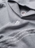 Close up view of Pieces Wired Sweatshirt Heather Grey hoodie showing the hood, neck tag, a small P star logo in the front, and the three barbed stripes running down the sleeve Pieces Wired Sweatshirt Heather Grey - Image 3 | Authenticated at Pieces Los Angeles