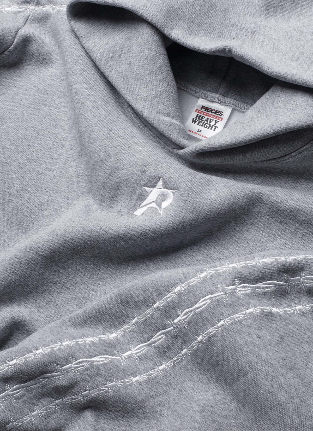 Close up view of Pieces Wired Sweatshirt Heather Grey hoodie showing the hood, neck tag, a small P star logo in the front, and the three barbed stripes running down the sleeve